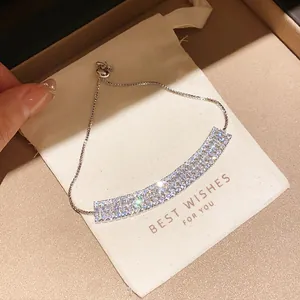 Detail view of a sparkling cubic zirconia adjustable bracelet resting on a beige gift pouch