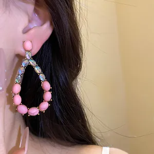 Primo piano di orecchini vintage a goccia con pietre rosa e cristalli indossati all'orecchio