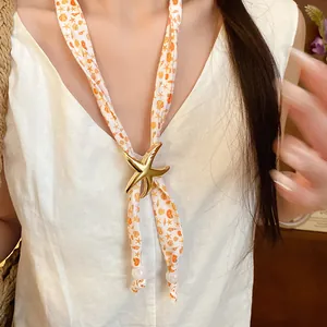 Detail of a marine style scarf necklace with a golden starfish slide and shell prints.