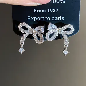 Primo piano di eleganti orecchini a fiocco in argento con pietre di zircone scintillanti