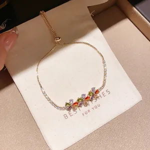 Detail view of colorful zircon flower charms on a delicate gold chain bracelet.