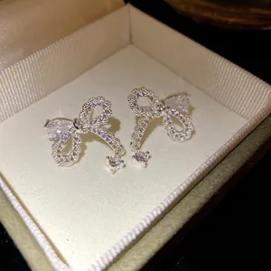Dettaglio ravvicinato di eleganti orecchini a fiocco in argento con zirconi scintillanti e perni