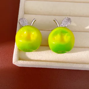 Detail shot of green resin apple charms with sparkling zircon leaves on a jewelry tray