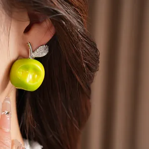 Close-up of a 3D green apple stud earring with zircon leaf detail worn by a model