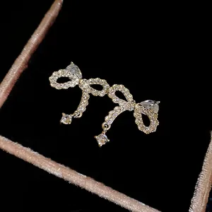Primo piano di orecchini a fiocco in zircone con pendenti su velluto nero di lusso.