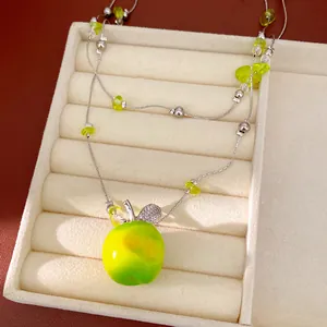Detailed view of double-layer beaded necklace with green resin apple pendant and zircon leaf