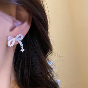 Dettaglio di un elegante orecchino a fiocco d'argento con zirconi brillanti e ciondolo.