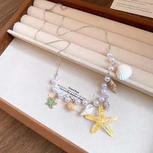 Close-up of beach-style necklace with faux pearls, seashells, and yellow starfish charms