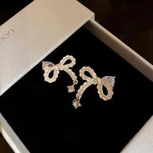 Dettaglio macro di orecchini a perno con fiocco in zircone lucido in una confezione regalo grigia