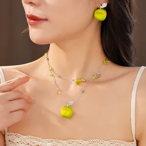 Close-up of double-layer beaded necklace and earring with green resin apple pendant
