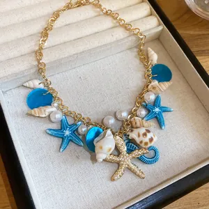 Detailed view of beach style gold necklace with pearls, shells and blue starfish charms
