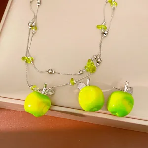 Detailed view of the double-layer beaded necklace and matching green resin apple earrings.