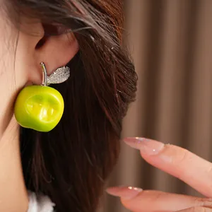 Close-up of green resin apple earring with sparkling zircon leaf detail on ear