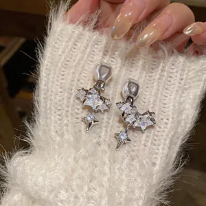 Close-up detail of 14k gold plated star zircon clip-on earrings on a white sweater sleeve