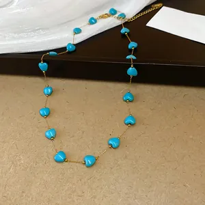 Detailed macro view of turquoise heart beads on a delicate gold-tone link chain necklace
