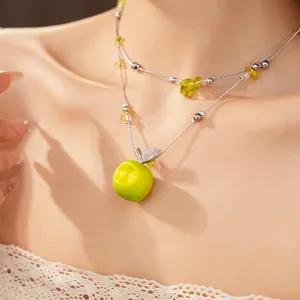 Detailed view of a double-layered necklace featuring a lime green resin apple pendant.