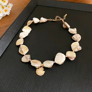 Close-up of beach style choker necklace with irregular shells and gold shell pendant