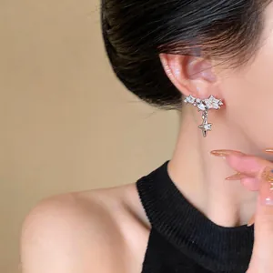 Close-up view of exquisite dangling star earrings with shiny zircon on a model's ear