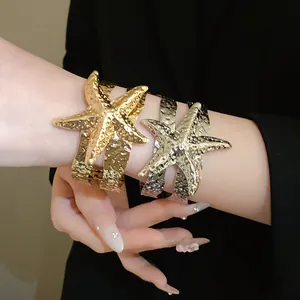 Dettaglio ravvicinato di bracciali aperti a stella marina martellata in oro e argento
