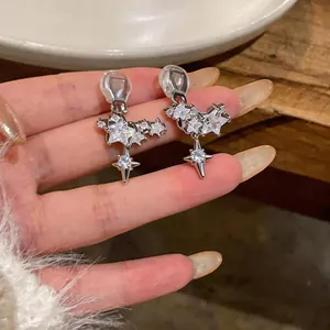 Close-up of star-shaped clip-on earrings with sparkling zircons and gold plating.