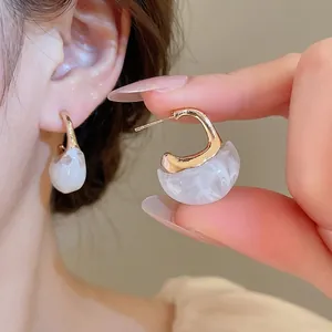 Elegant vintage C-shaped resin hoop earrings with gold accents and white marble texture