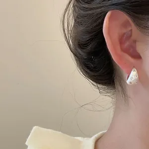 Gros plan sur des créoles minimalistes en argent brossé avec des motifs d'étoiles gravés