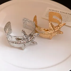 Vista dettagliata dei bracciali a polsino a stella marina in oro e argento.