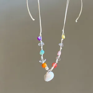 Detail of beach style necklace with colorful beads and a white seashell pendant