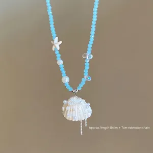 Close-up of blue beaded necklace with shell pendant and pearl details