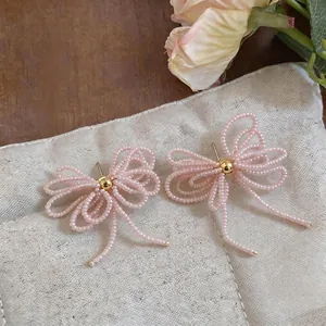 Boucles d'oreilles noeud en perles de verre rose avec aiguilles argent et perle dorée
