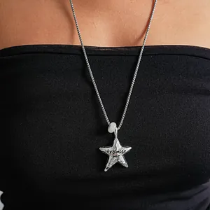 Gros plan détaillé d'un collier pendentif étoile argentée froissée avec gravure Promise me
