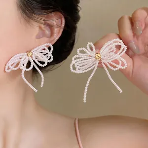 Élégantes boucles d'oreilles nœud en perles blanches avec centre doré et aiguilles en argent S925
