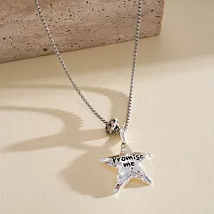 Détail d'un pendentif étoile argenté froissé avec gravure Promise me et perle de pierre