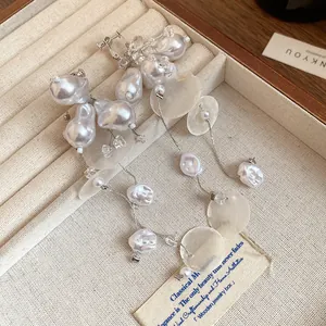 Primer plano de pendientes de clip retro franceses con perlas barrocas y borlas de nácar