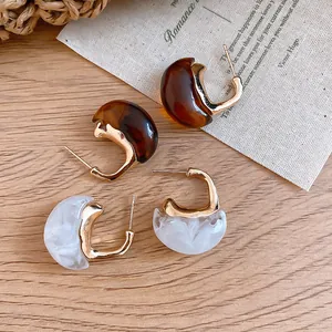 Detailed macro view of vintage Maillard resin C-shaped earrings in amber and white marble