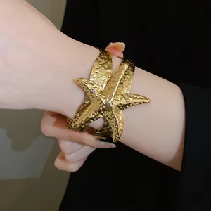 Dettaglio ravvicinato di un bracciale a polsino a forma di stella marina dorata con texture martellata