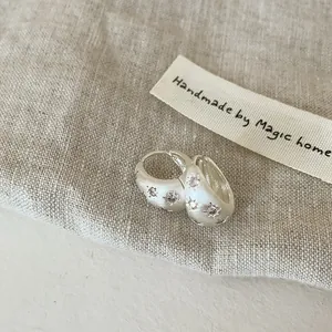 Gros plan de boucles d'oreilles créoles en argent mat avec motif étoile en zircon.