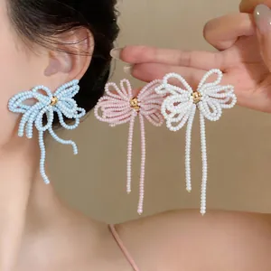 Vue détaillée de ces boucles d'oreilles nœuds en perles faites main en bleu, rose et blanc