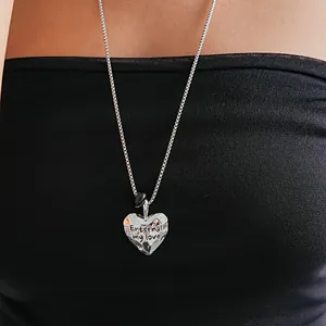 Gros plan d'un pendentif en forme de cœur argenté froissé avec un message gravé.