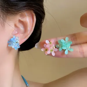 Vue rapprochée de boucles d'oreilles fleuries en bleu, rose et vert
