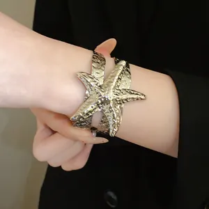 Primo piano di un bracciale a fascia a stella marina dorata su una manica nera.