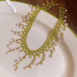 Detailed view of a handmade green beaded fringe necklace with pink flower charms