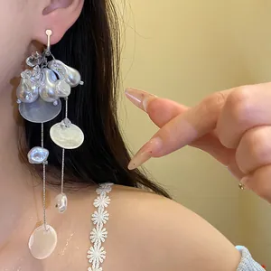 Primer plano de pendientes de clip vintage con perlas y flecos de concha en modelo.