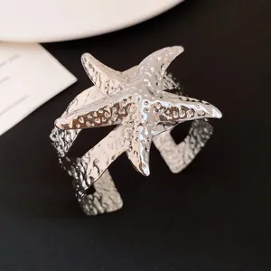 Primo piano di un bracciale rigido a forma di stella marina in argento testurizzato.