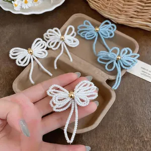 Gros plan de la boucle d'oreille en perles blanches faite à la main en nœud.