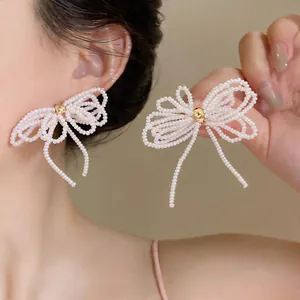 Vue détaillée de boucles d'oreilles nœud perles faites main avec perles blanches