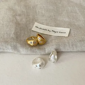 Détail montrant la texture brossée et le motif d'étoile en zircone sur les boucles