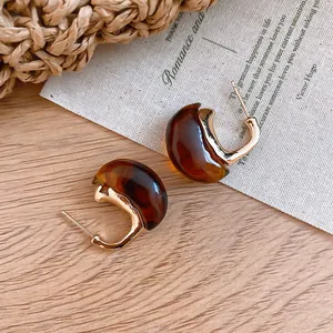 Close-up detail of vintage tortoiseshell resin C-shaped hoop earrings with gold finish.