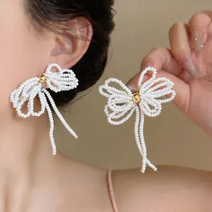Vue détaillée de boucles d'oreilles nœud en perles blanches faites à la main avec aiguille