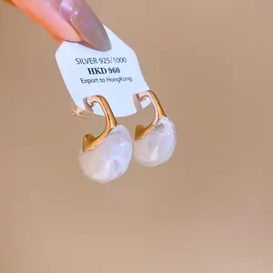 Close-up view of elegant vintage resin C-shaped earrings with white marble pattern on a tag